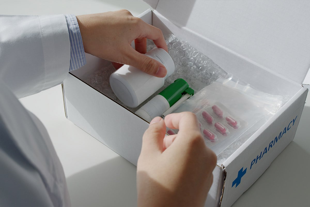 Hands putting pharmacy items in box in brightly lit room