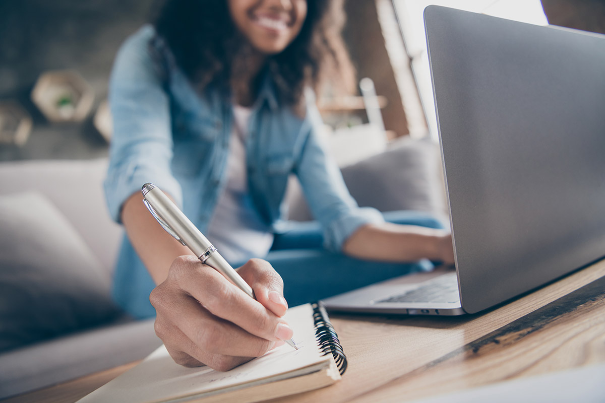 woman on laptop writing notes