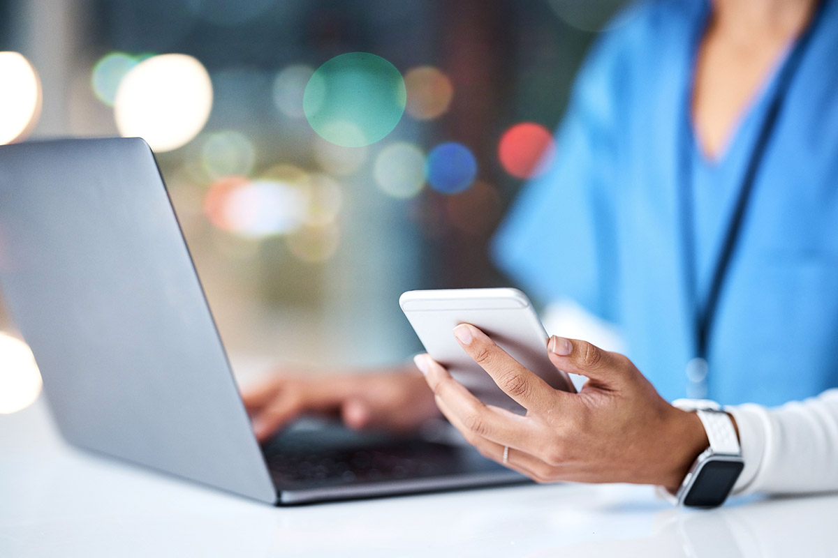 close up of a nurse using their smartphone and laptop